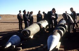 Soviet inspectors and their American escorts stand among several dismantled Pershing II missiles as they view the destruction of other missile components, 1989. [Wikimedia Commons]
